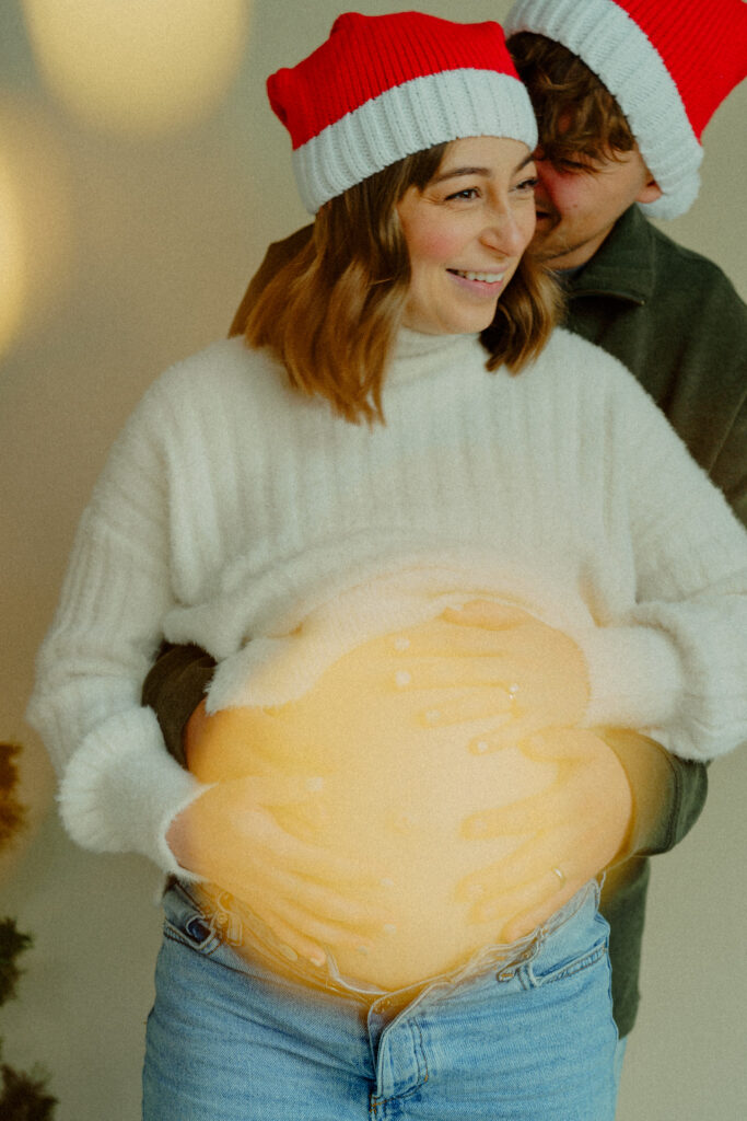Expecting couple cradling baby bump with light leaks in the image