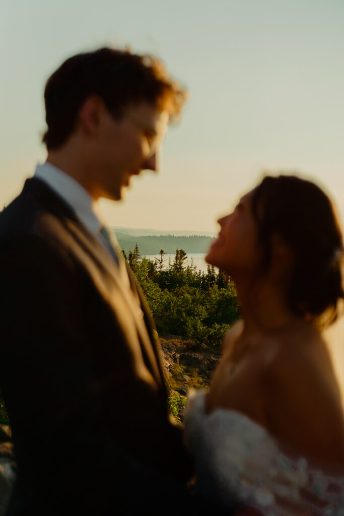waist up shot of eloping couple smiling at each other while they are out of focus and the scenery behind them is in focus