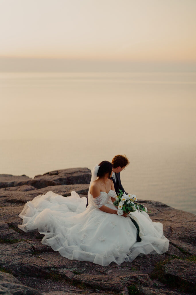 Eloping couple sitting by cliff and watching the water