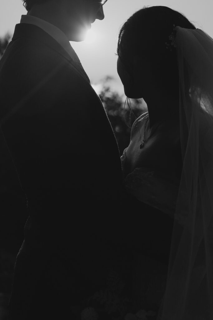 black and white image waist up of eloping couple watching sun rise