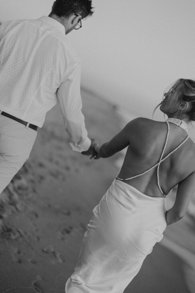 couple holding hands and walking on the beach at windsnest park