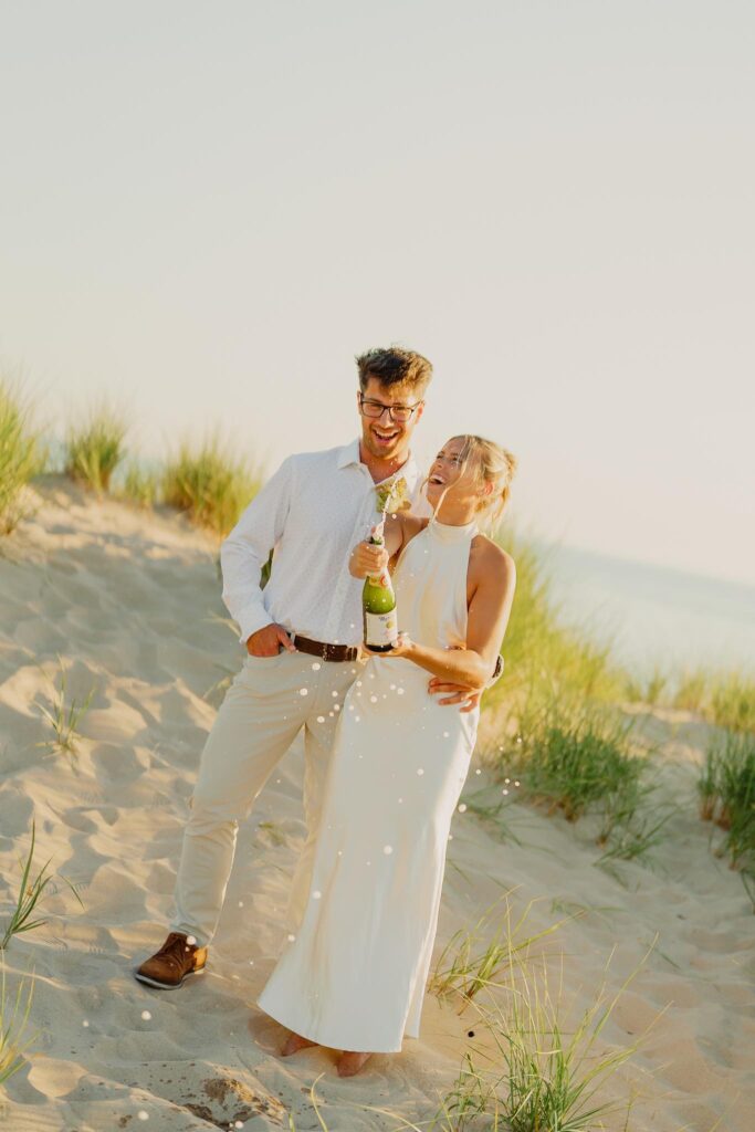 couple popping champagne on the michigan sand dune