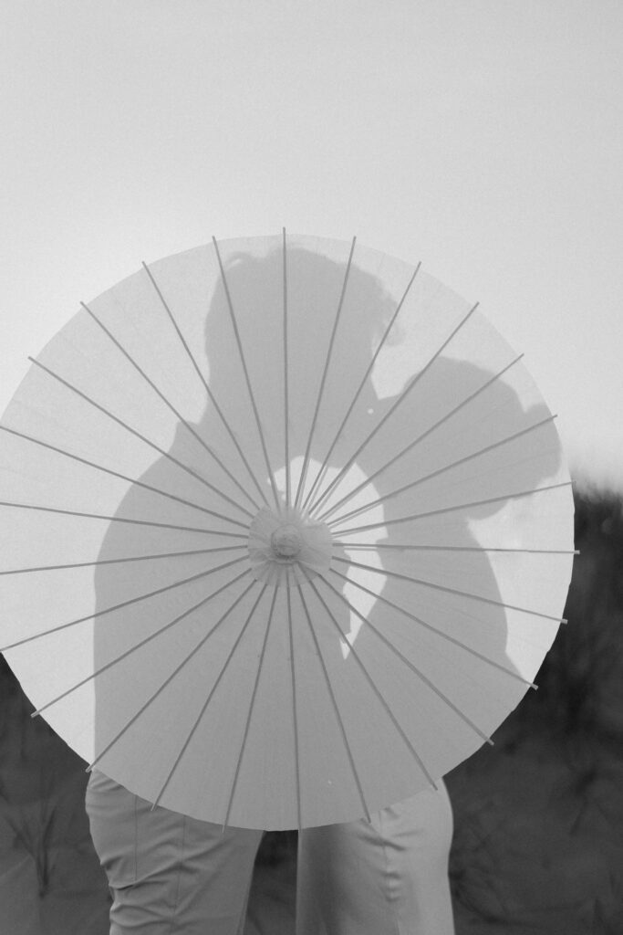 couple kissing behind an umbrella with a silhouette showing them kiss