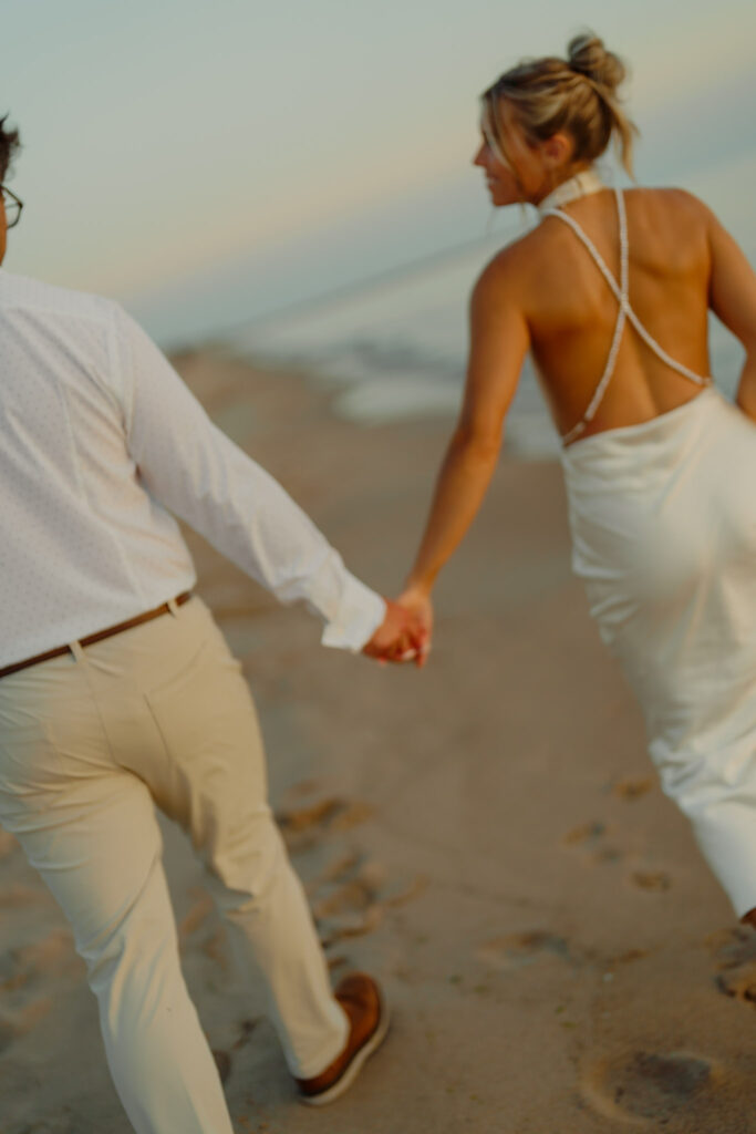 Couple holding hands and walking on beach and woman smiling at man