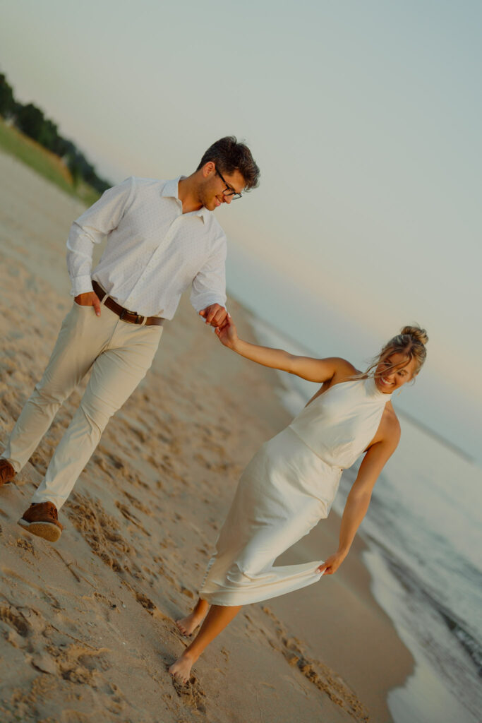 Man and woman holding hands and walking on the beach, woman holds dress with her free hand