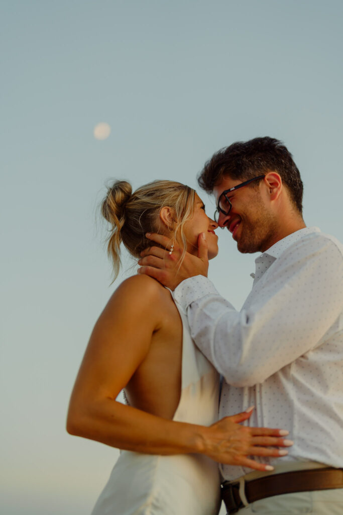 couple smiling while in warm embrace at windsnest beach
