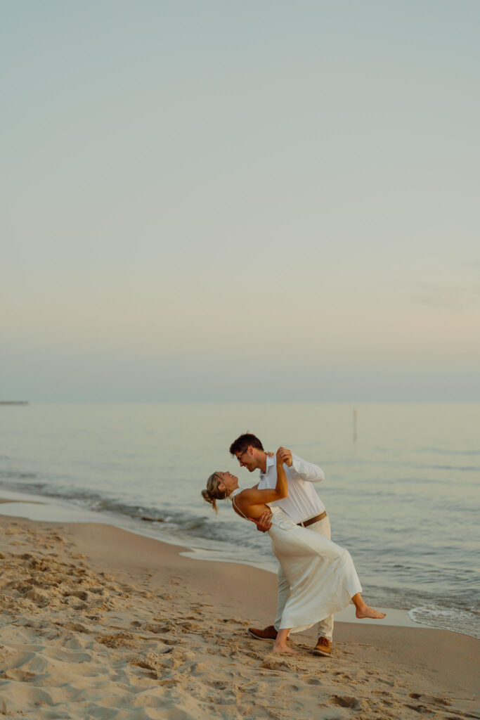 man dipping woman on the beach
