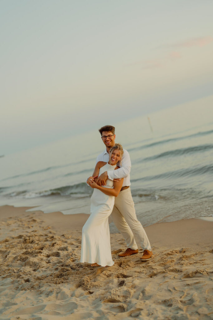 Couple embracing at Michigan beach and smiling deeply