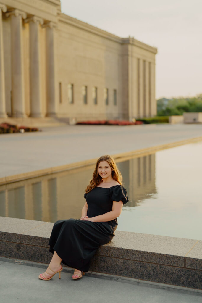 Modern Kansas City business headshots with waterfront backdrop at Nelson-Atkins sitting on marble an smiling