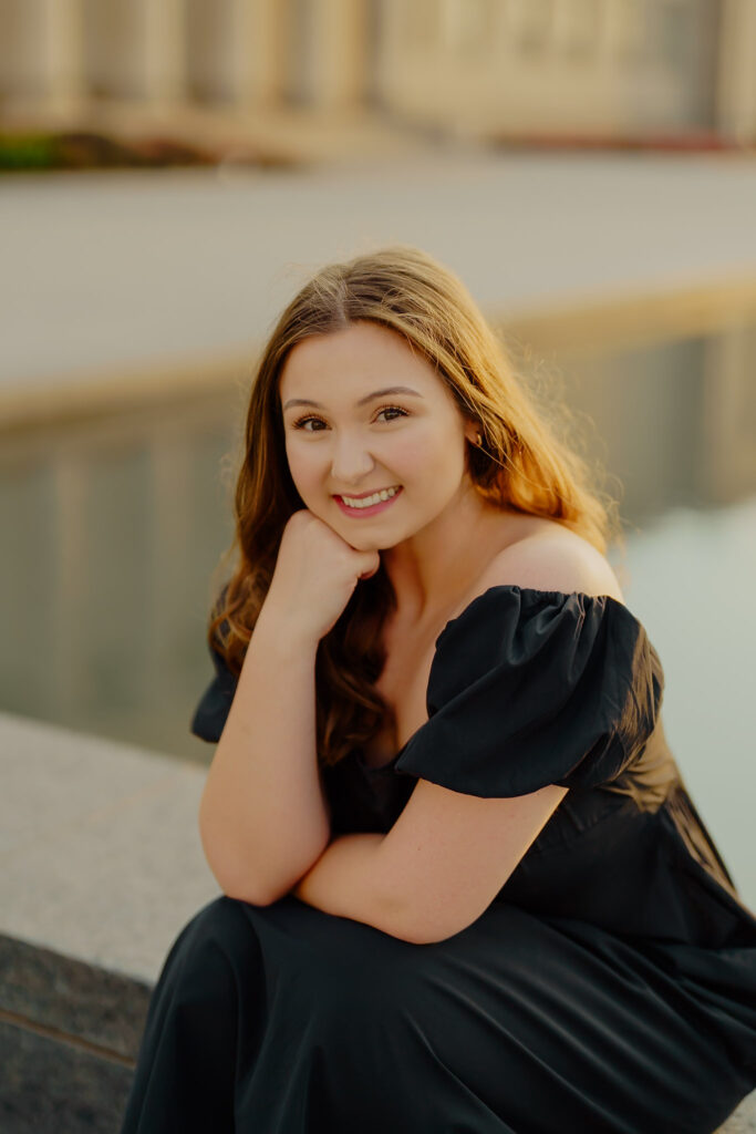 Modern Kansas City business headshots with waterfront backdrop at Nelson-Atkins sitting on marble an smiling