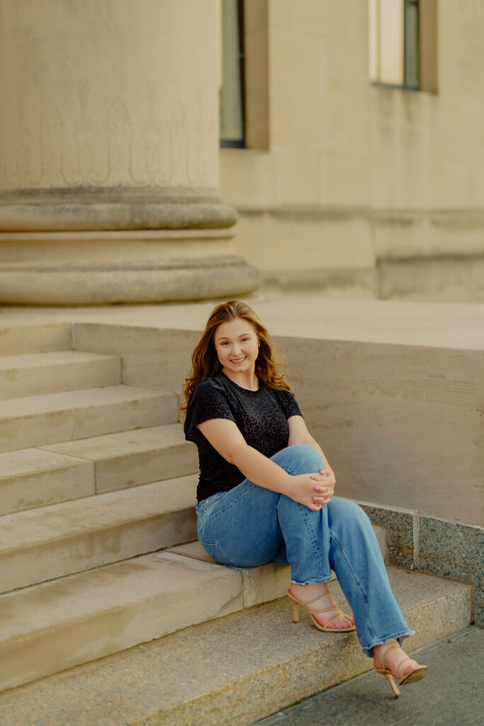 Confident professional headshot with architectural backdrop at Nelson-Atkins Museum sitting by column stairts