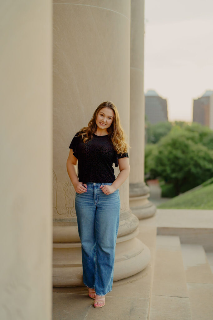 Corporate portrait of woman smiling in natural light at Nelson-Atkins Museum standing by columns