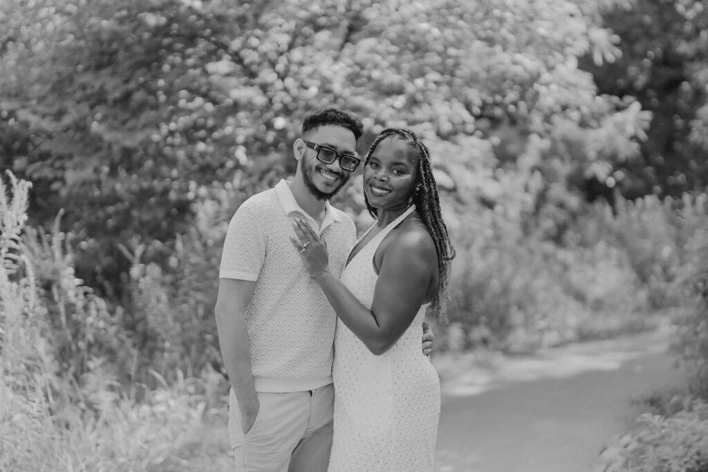 Surprise proposal at Powell Gardens, couple smiling at camera black and white